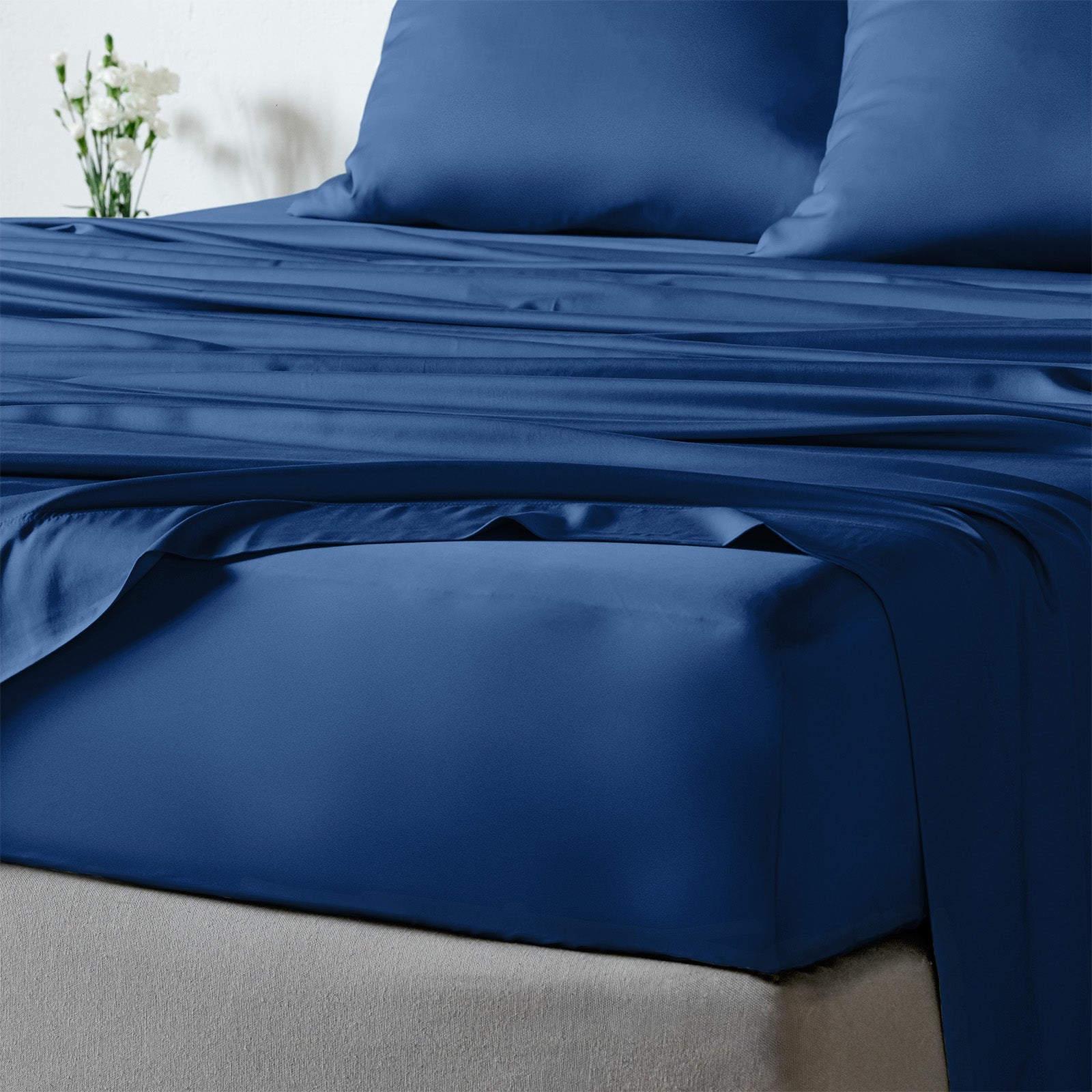 bambaw cozy bamboo bed sheets close up on a bed with fitted sheets and pillows in navy blue colour