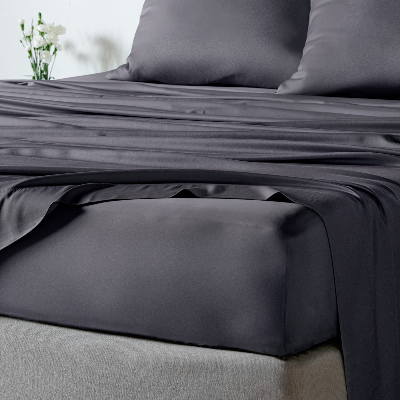 bambaw cozy bamboo bed sheets close up on a bed with fitted sheets and pillows in dark grey colour