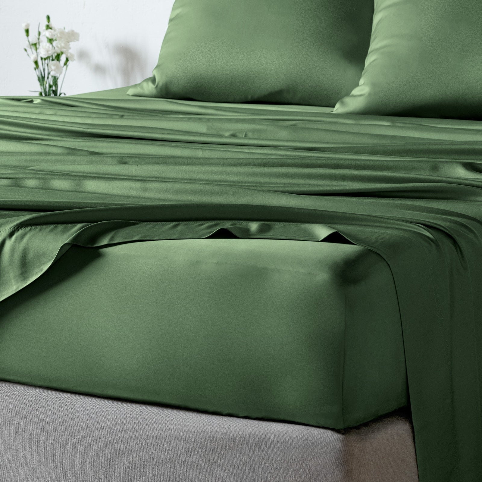 bambaw cozy bamboo bed sheets close up on a bed with fitted sheets and pillows in olive green colour