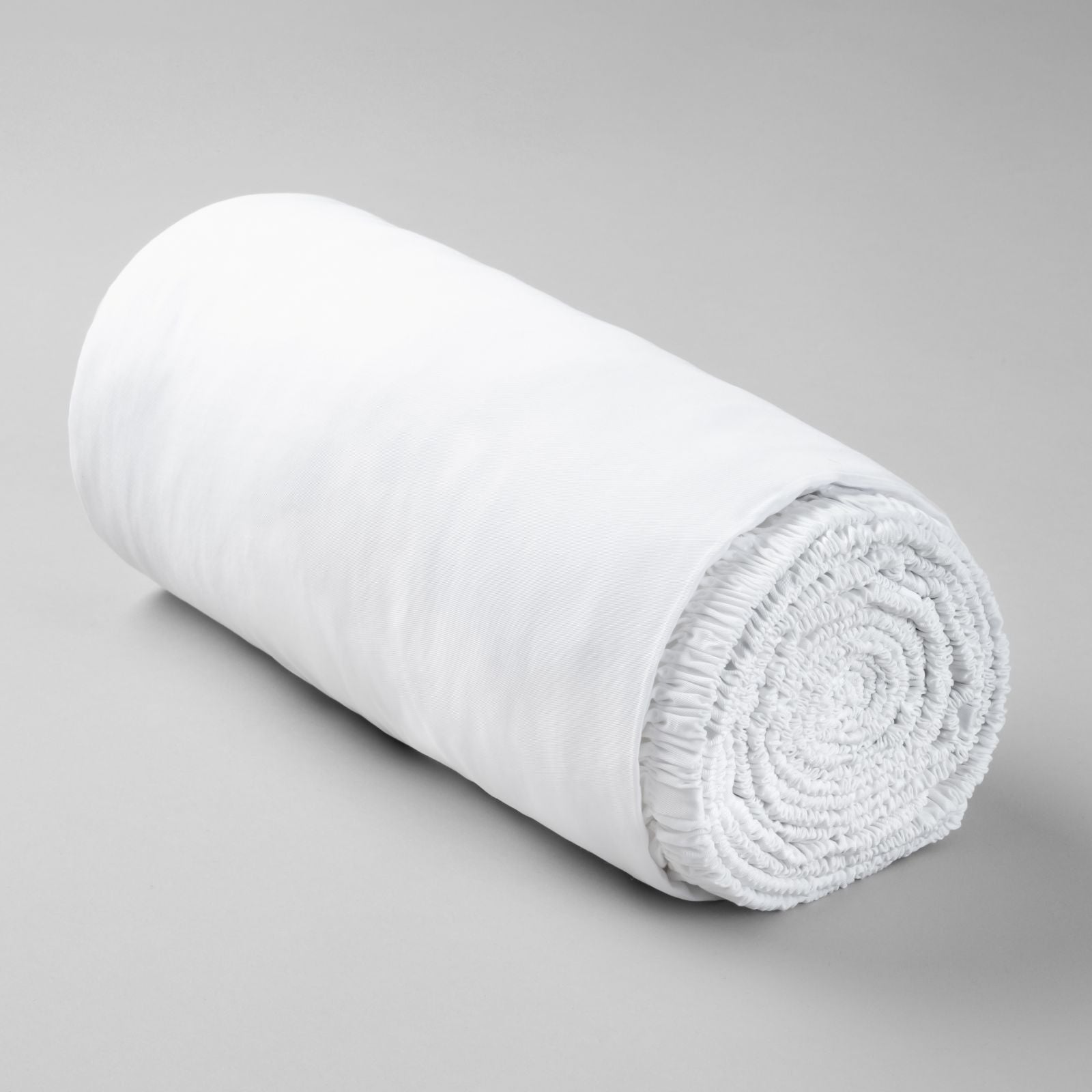 Rolled-up white bamboo fitted sheet on a gray background
