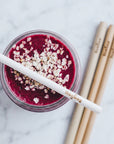 Purple smoothie in a jar with a bamboo straw across the rim