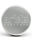 Silver shampoo box tin with 'arista ayurveda' branding on a white background