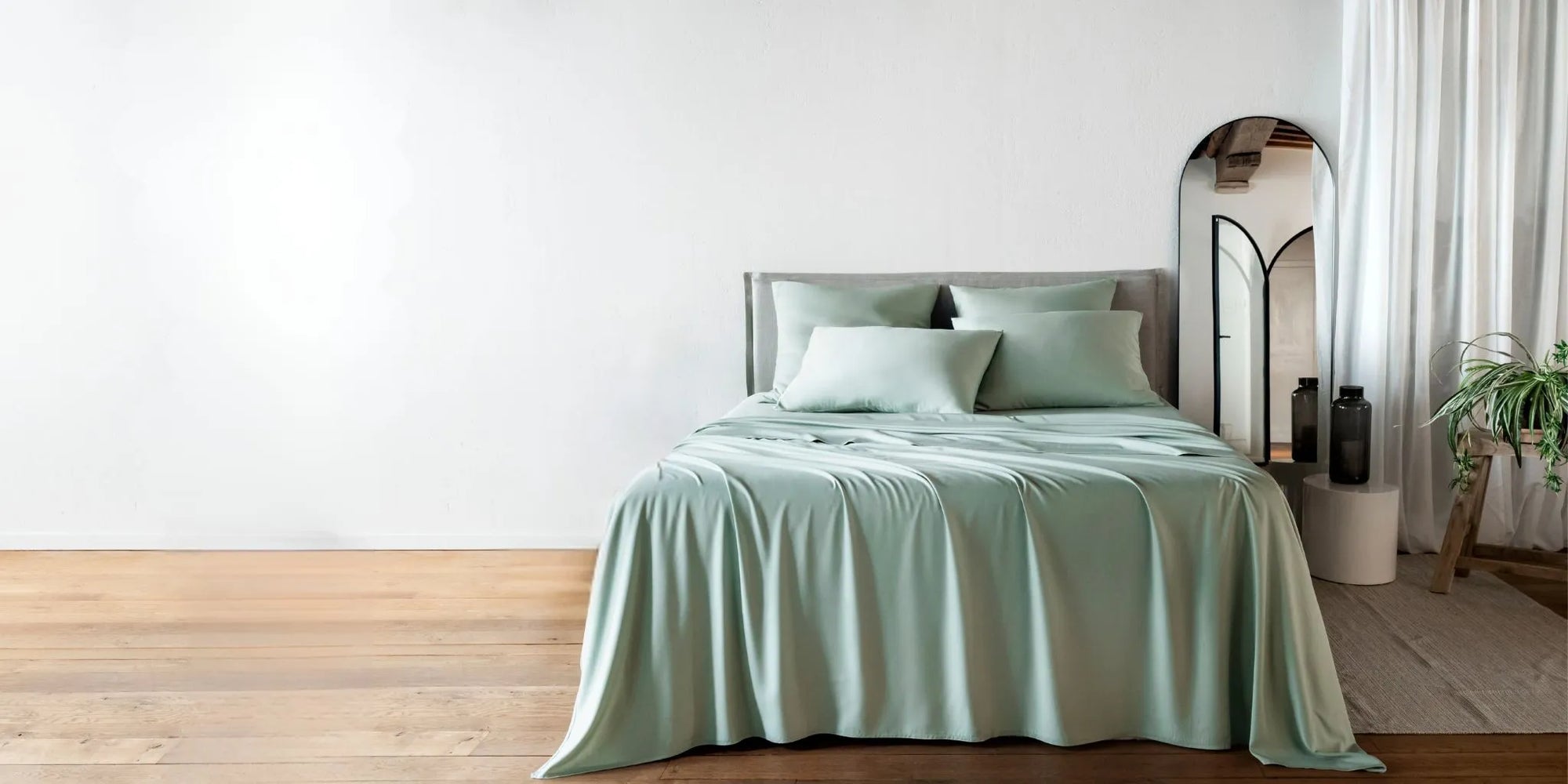 Bed with light green bamboo bedding in a minimalistic bedroom setting
