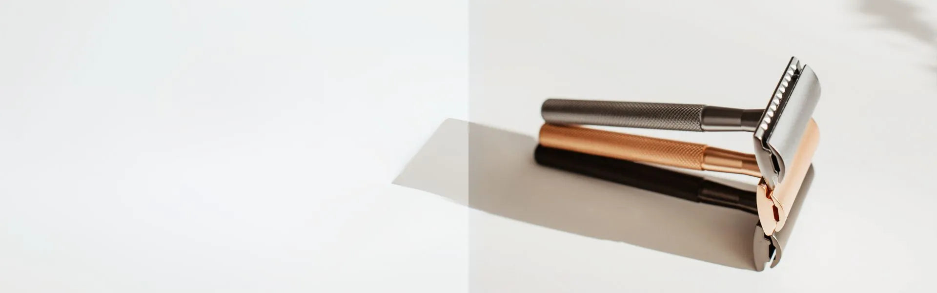 Rose gold, silver and black metal safety razors on a white background